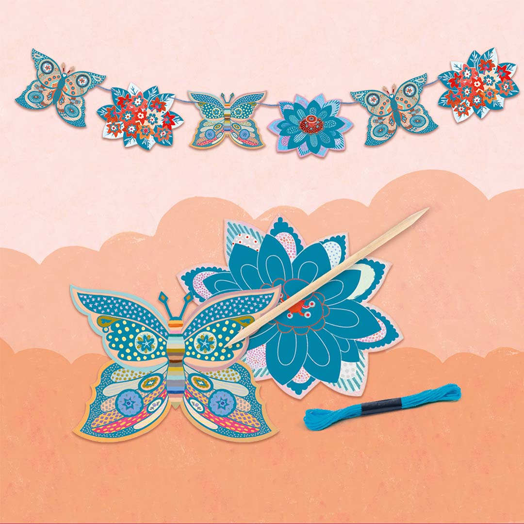 Een knutselactiviteit van de Djeco set met een houten prikker, blauw garen en papieren vlinders en bloemen om een slinger te maken.