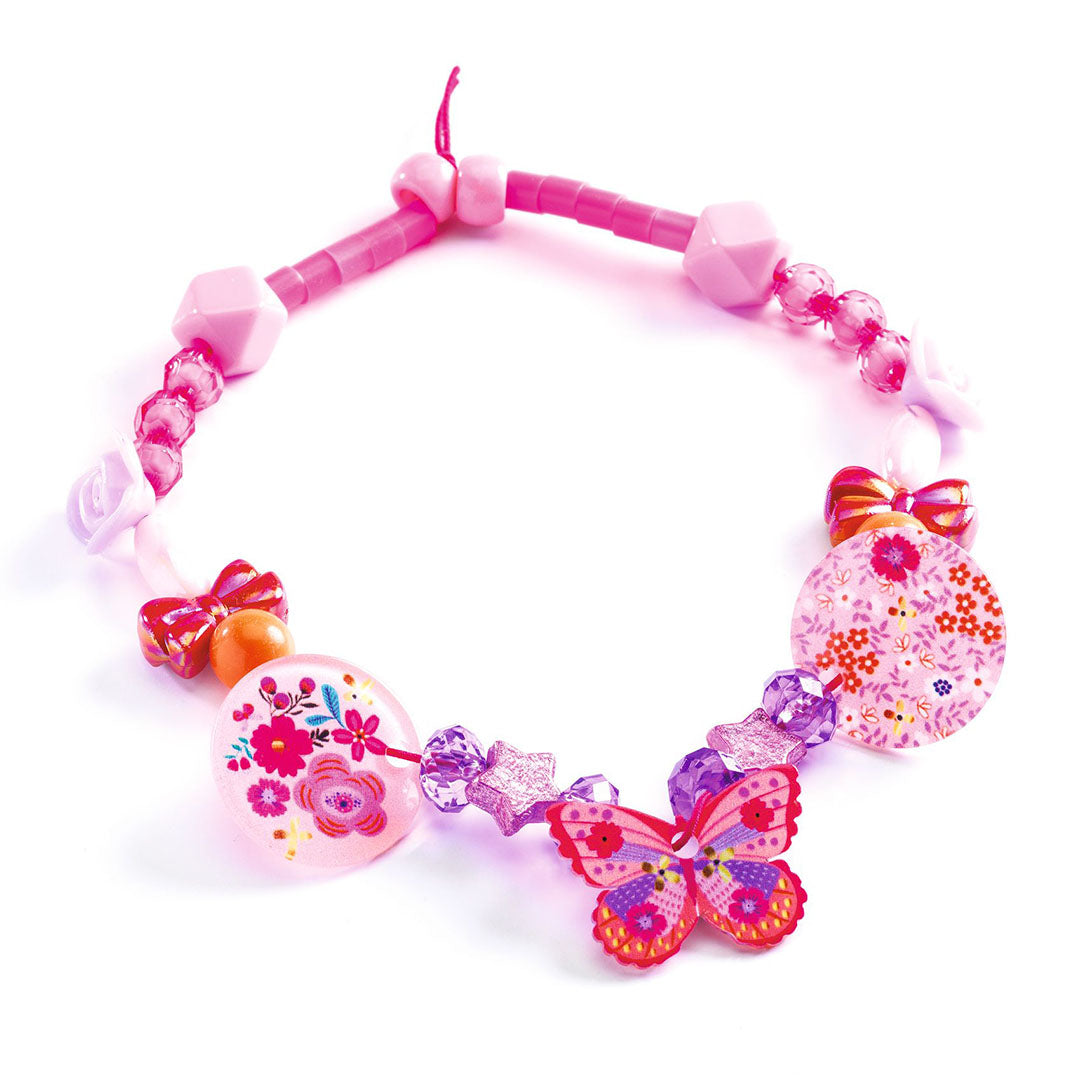 Een gemaakte kralenketting met roze en paarse vlinder- en bloemenbedels.