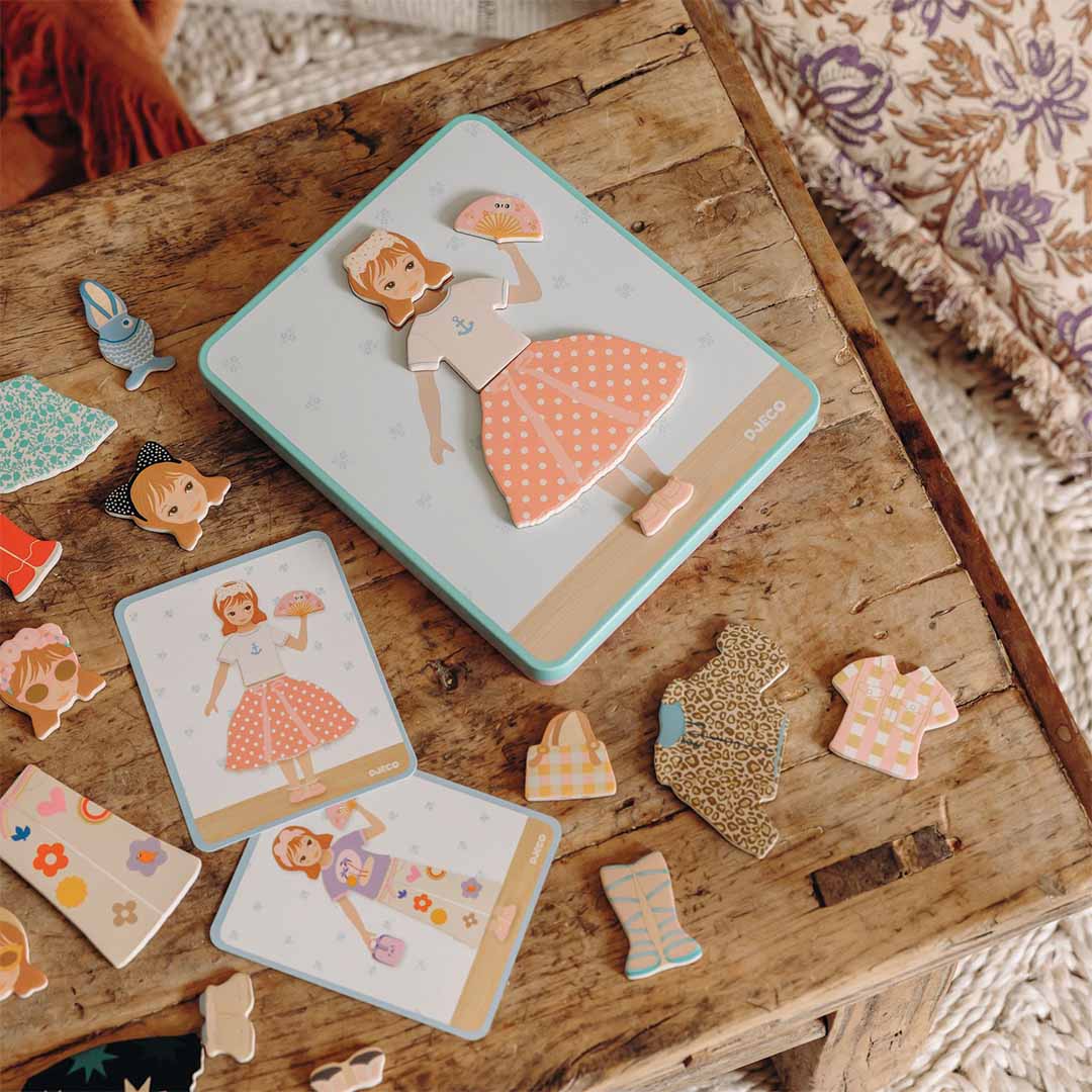 Djeco magneetset inzebox dressing met een aangeklede pop en losse kledingstukken op een houten tafel.