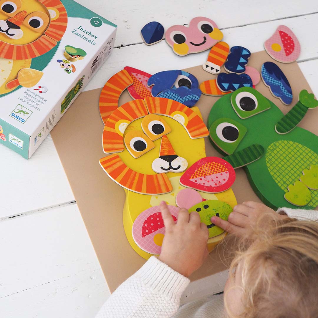 Een kind speelt met de Djeco Inzebox Zanimals houten magneetpuzzel, waarbij een leeuw en een krokodil worden gemaakt.