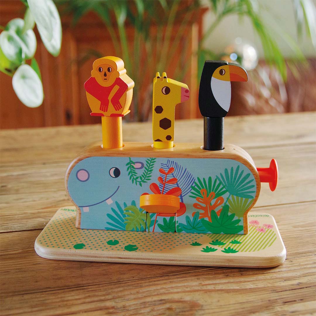 Djeco houten pop-up spel met safari dieren op een houten tafel, waarbij de aap, toekan en giraffe omhoog staan.
