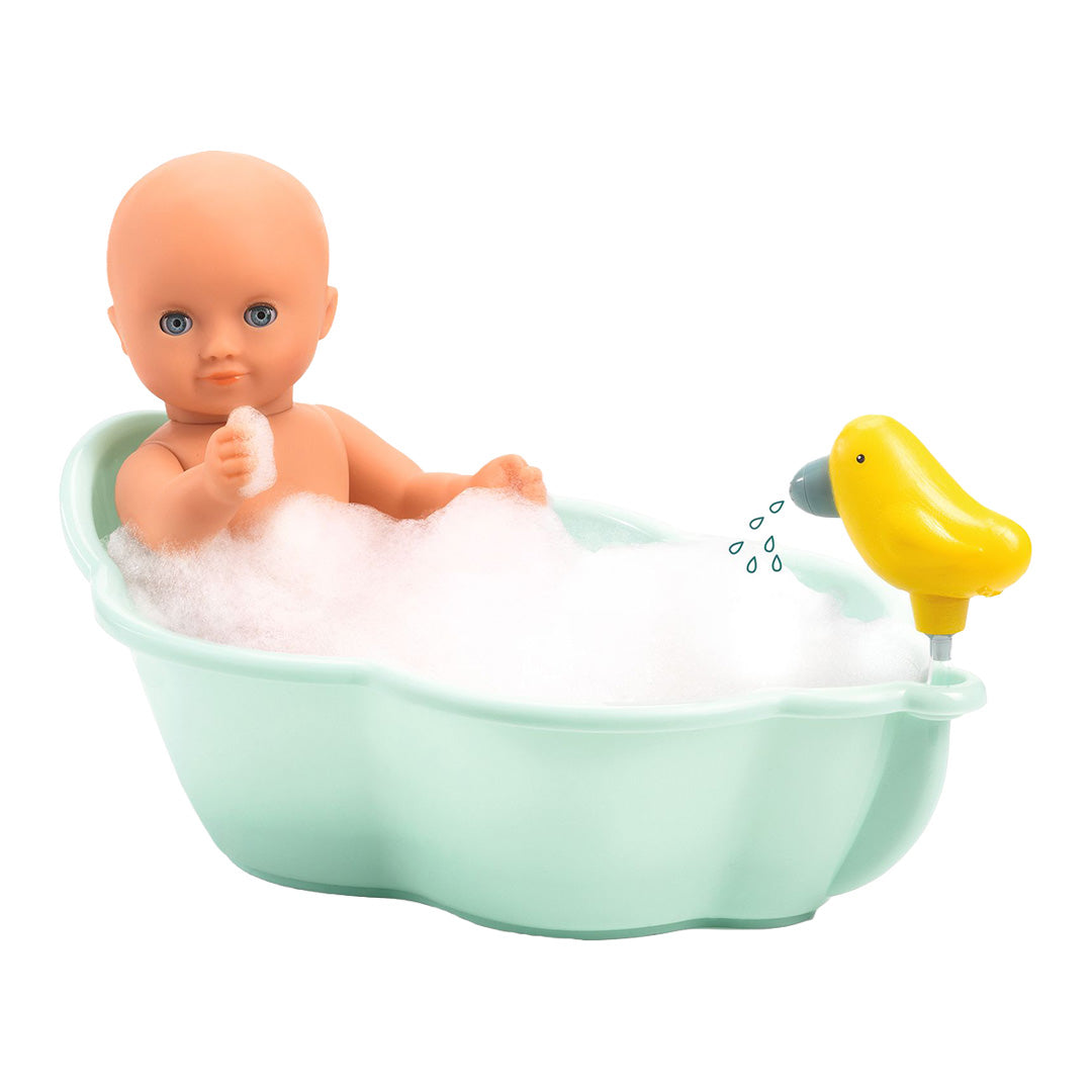 Een pop zit in het Djeco poppenbadje vol schuim, met de gele eend-douchekop die water spuit.