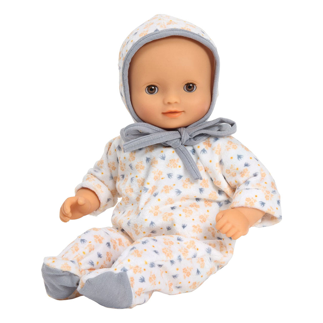 Een babypop draagt de Djeco poppenkledingset met gebloemde romper en mutsje.