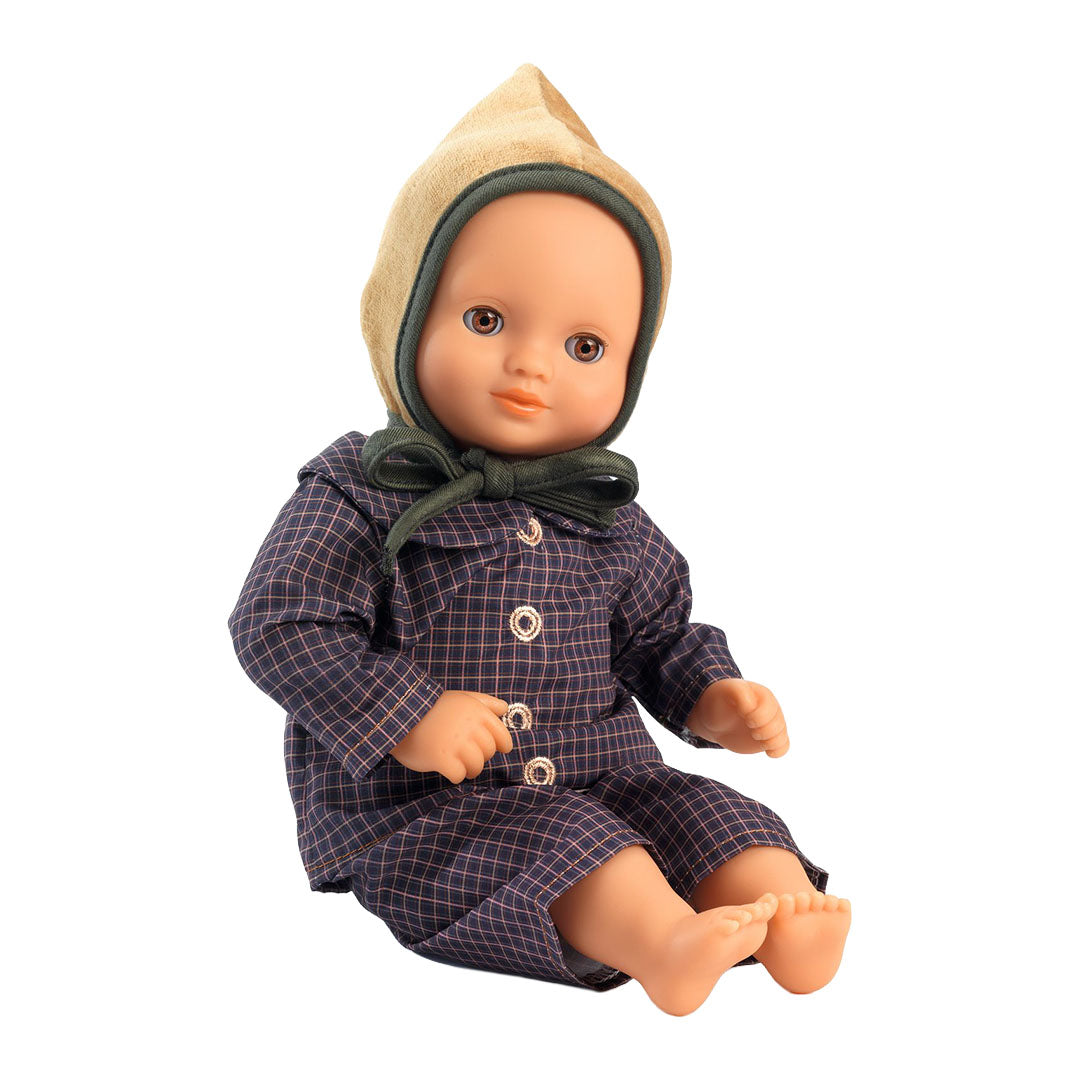 Een pop draagt de Djeco poppenkledingset Ambre met geruite top, broek en beige muts.