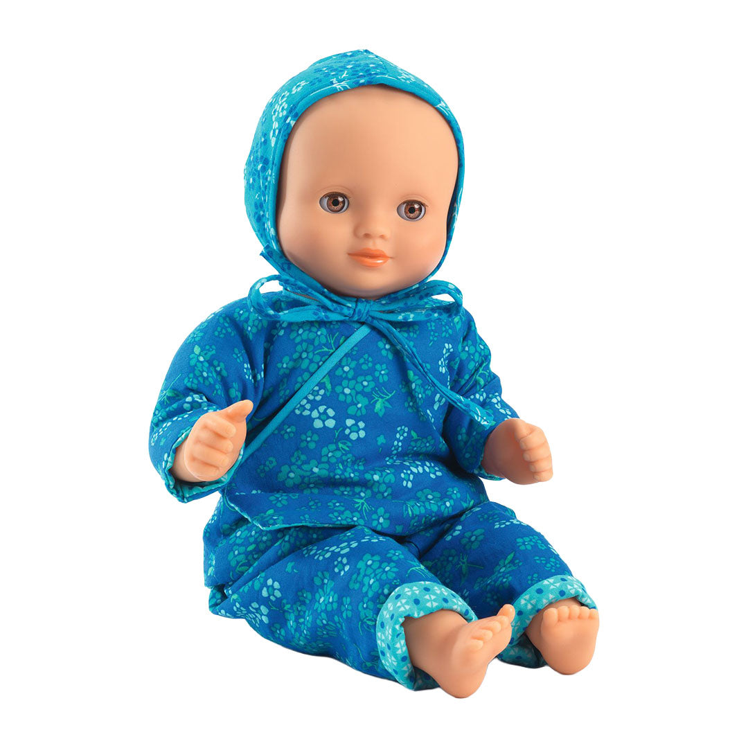 Een zittende pop draagt de Djeco blauw gebloemde poppenkledingset.