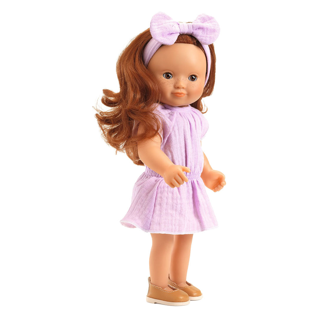 Een pop met rood haar draagt de violette Djeco poppenkleding set.