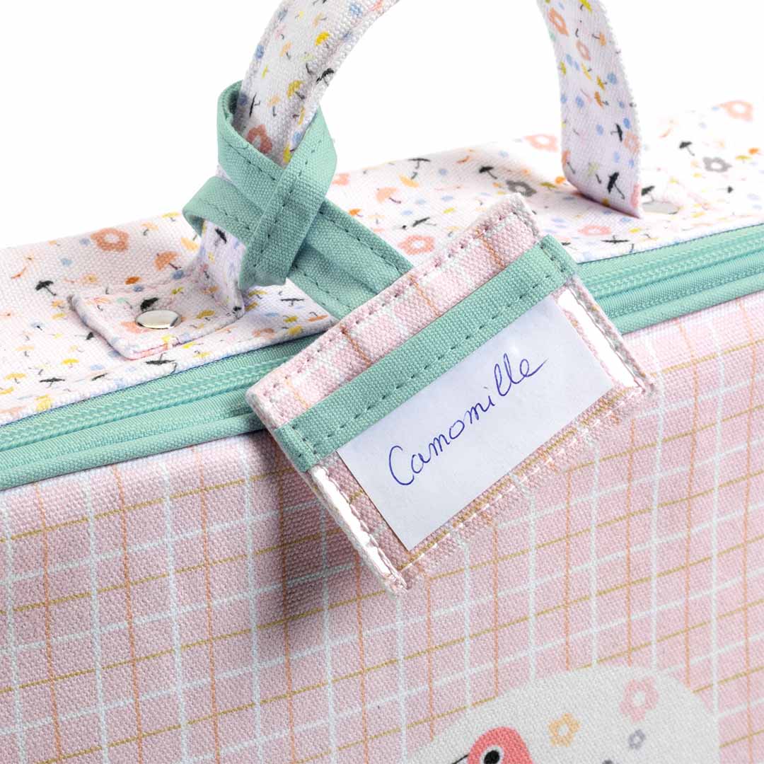Detail van de Djeco poppenkoffer met het handvat en een naamlabel met 'Camomille'.