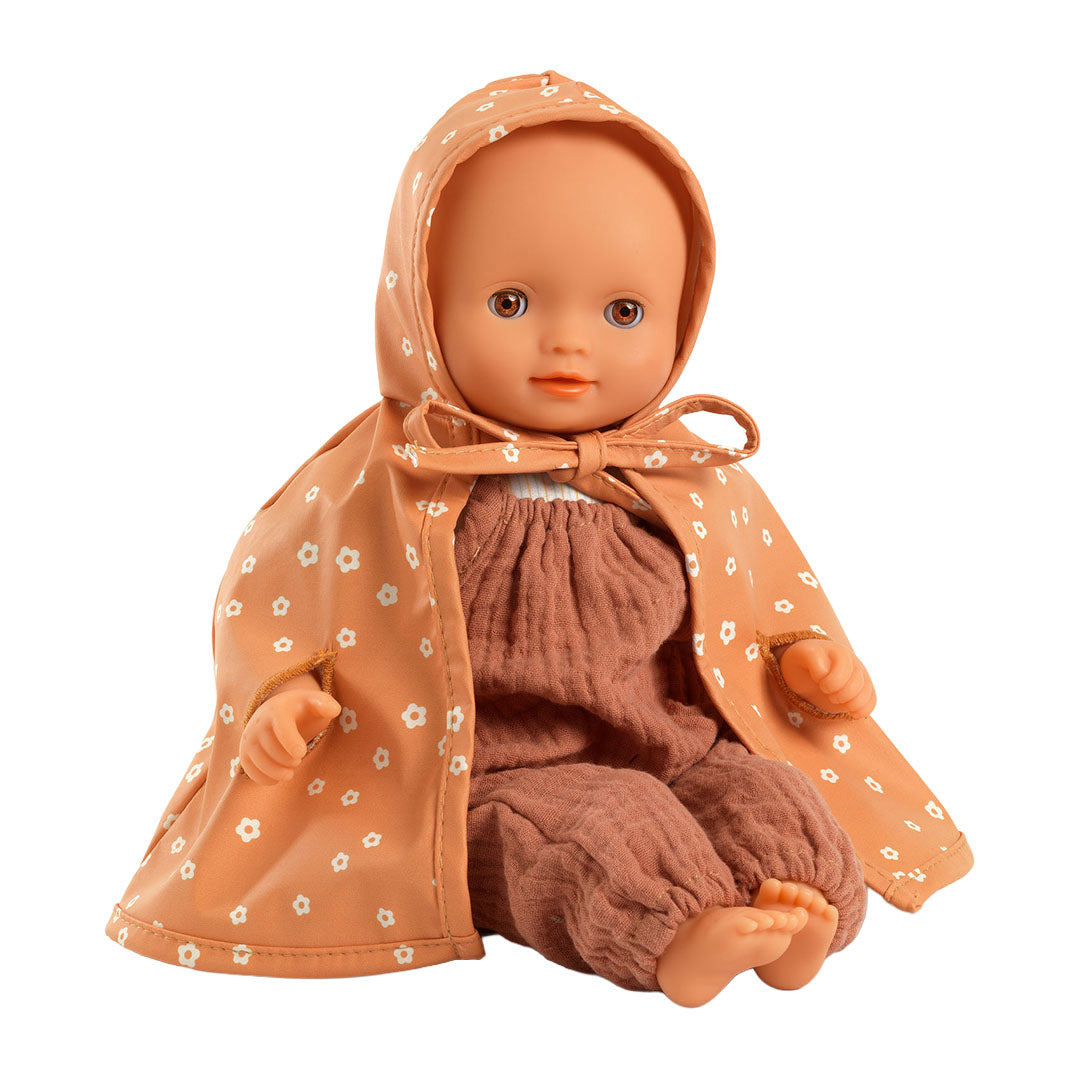 Djeco oranje gebloemde poppenregencape gedragen door een pop die zit.