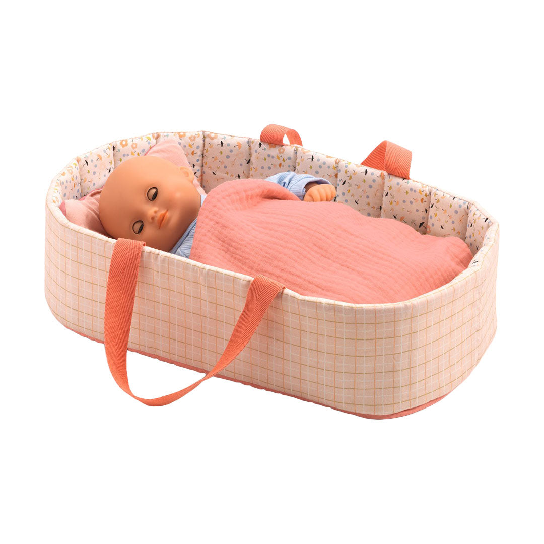 Djeco roze poppenreiswieg met een babypop erin, liggend onder een roze deken.