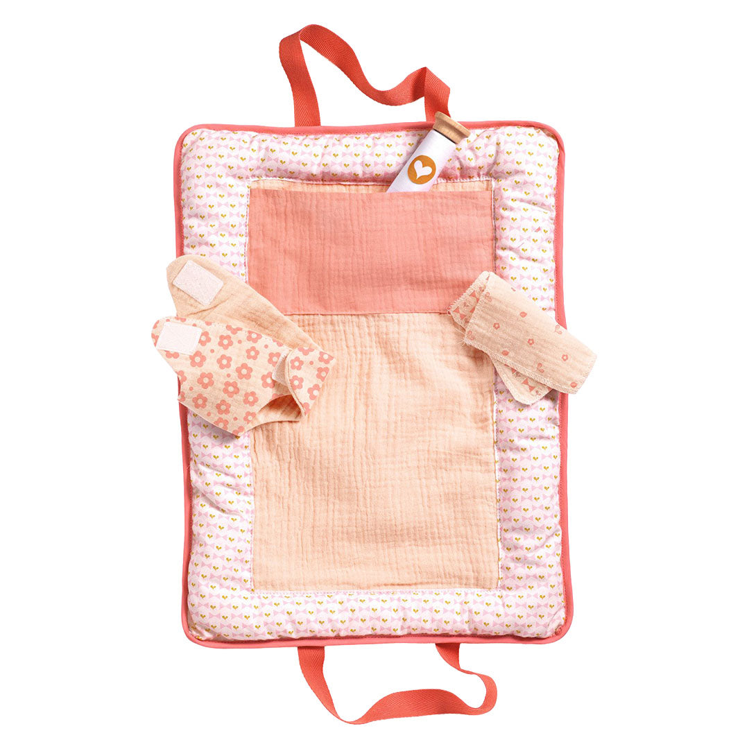 Djeco poppenverschoonset met een opengevouwen roze verschoonmatje met een flesje, luier en doekjes.