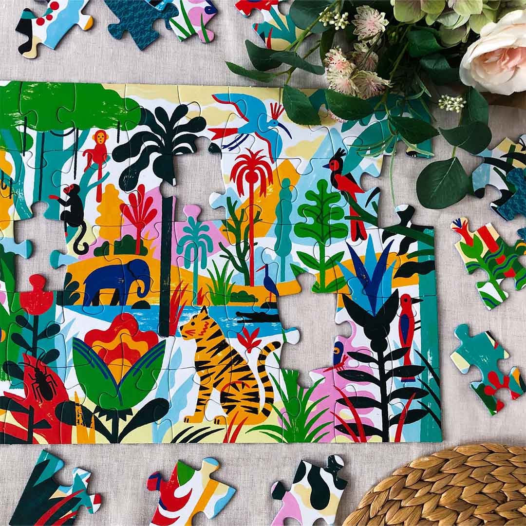Gedeeltelijk gelegde Djeco legpuzzel met jungle-thema, omringd door losse puzzelstukjes en bloemen.