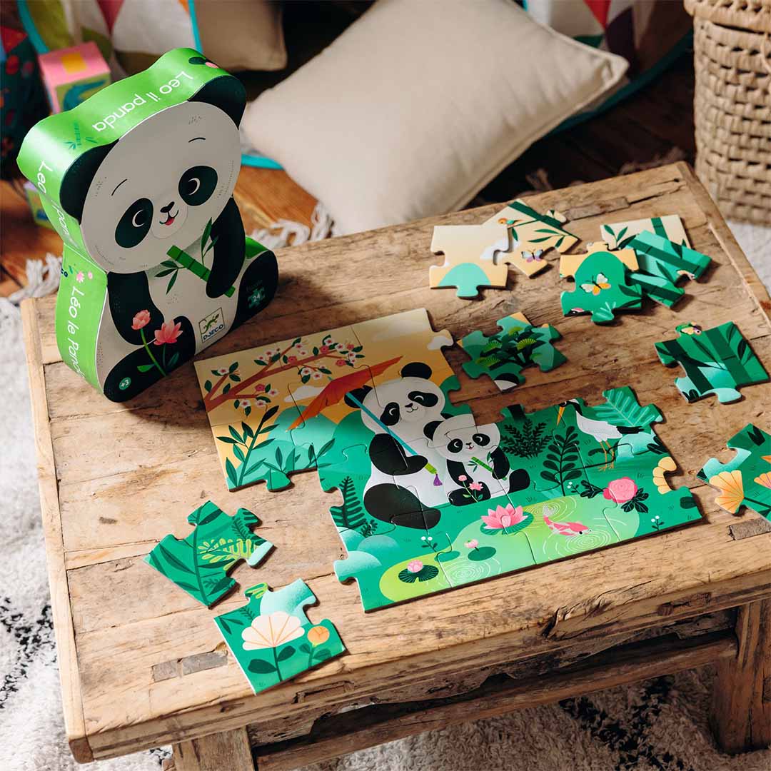 Een deels gelegde Djeco kinderpuzzel met panda's en losse stukjes op een houten tafel, met de panda-verpakking ernaast.