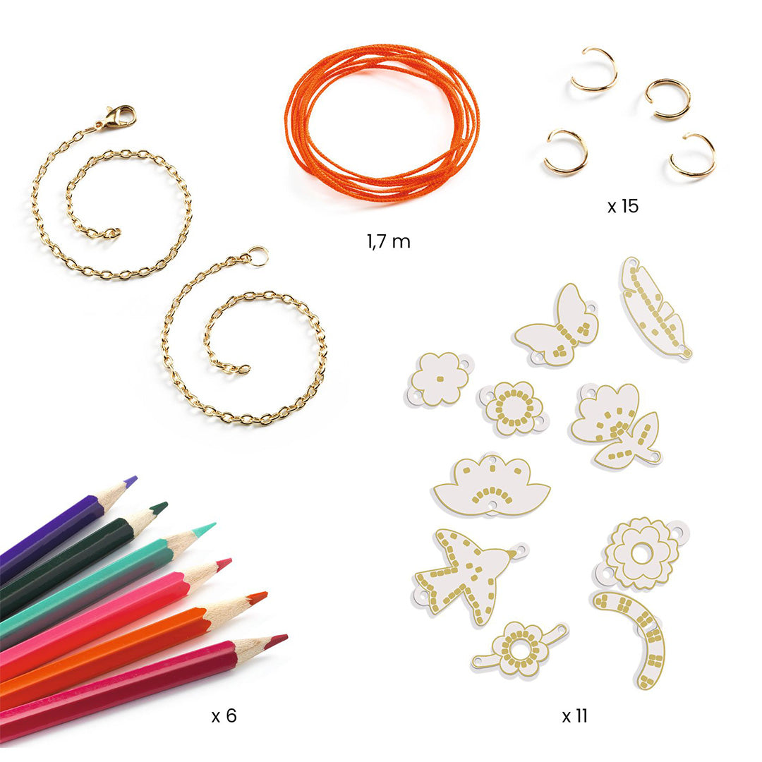 Onderdelen van de DJECO DIY sieradenset, waaronder kettingen, koord, ringen, kleurpotloden en witte plastic vormen van bloemen en dieren.
