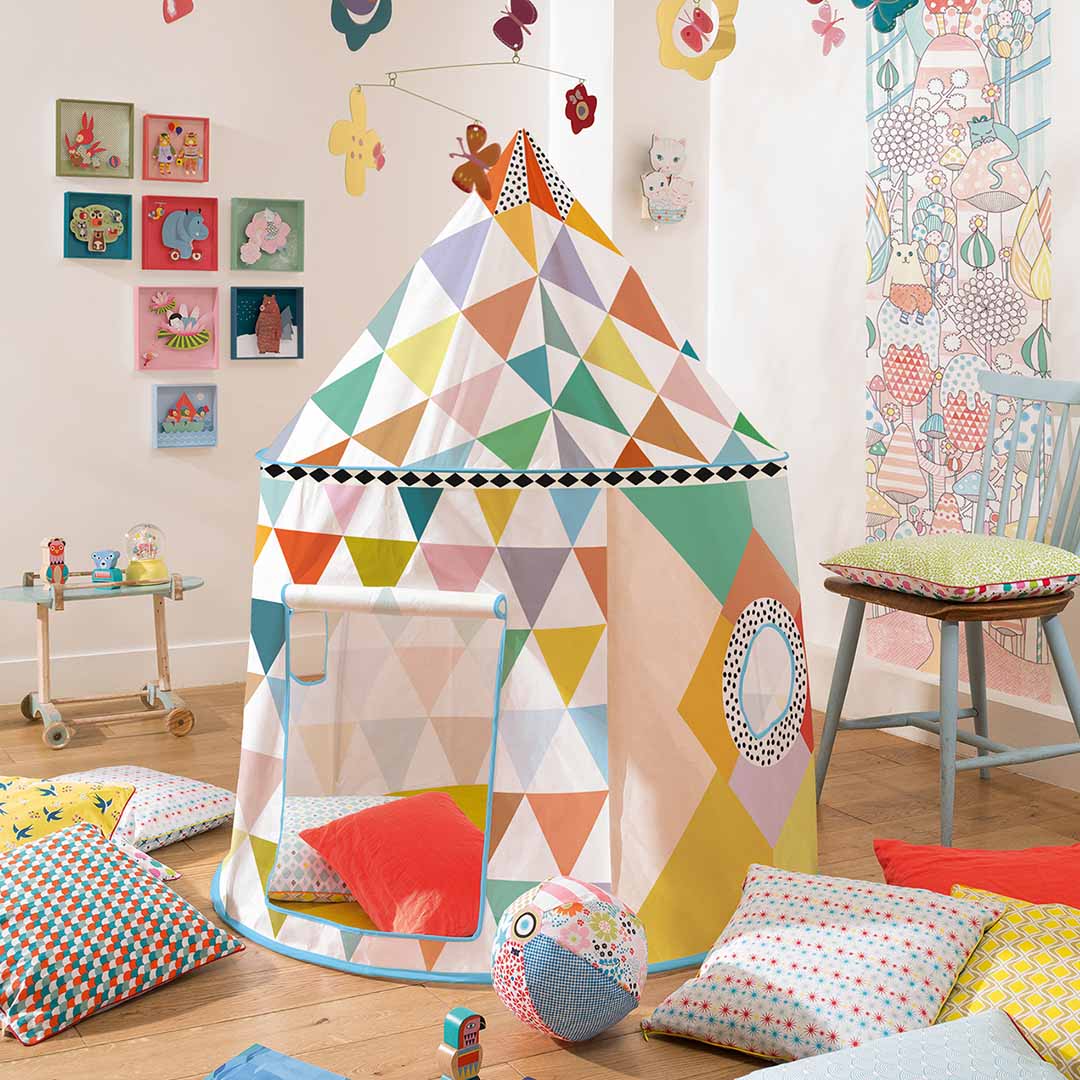 Djeco speeltent met veelkleurig geometrisch patroon in een kinderkamer met kussens en speelgoed.