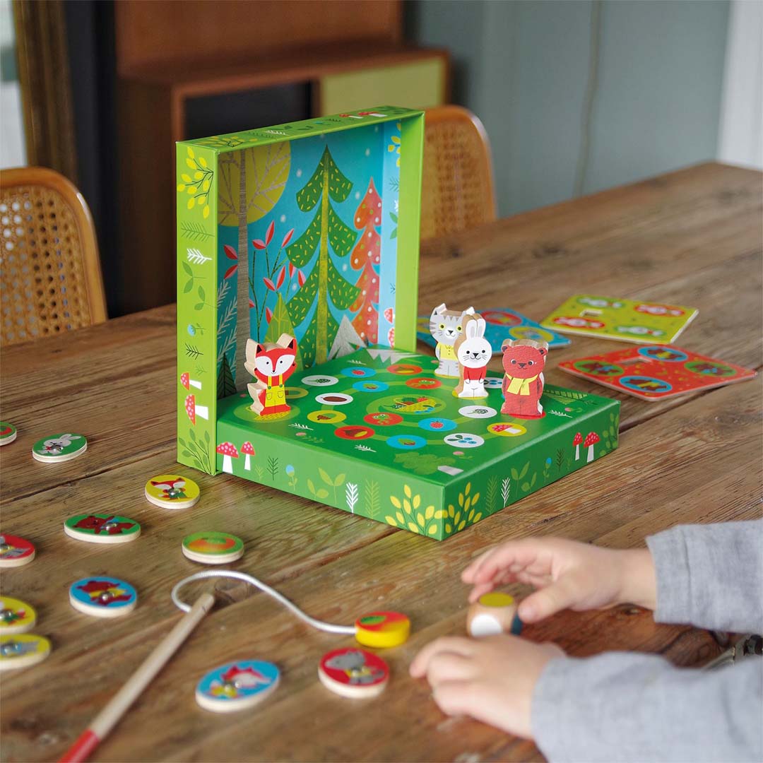 Kind speelt met het Djeco Ludo Wood houten bordspel met bosdierenfiguren op een houten tafel.