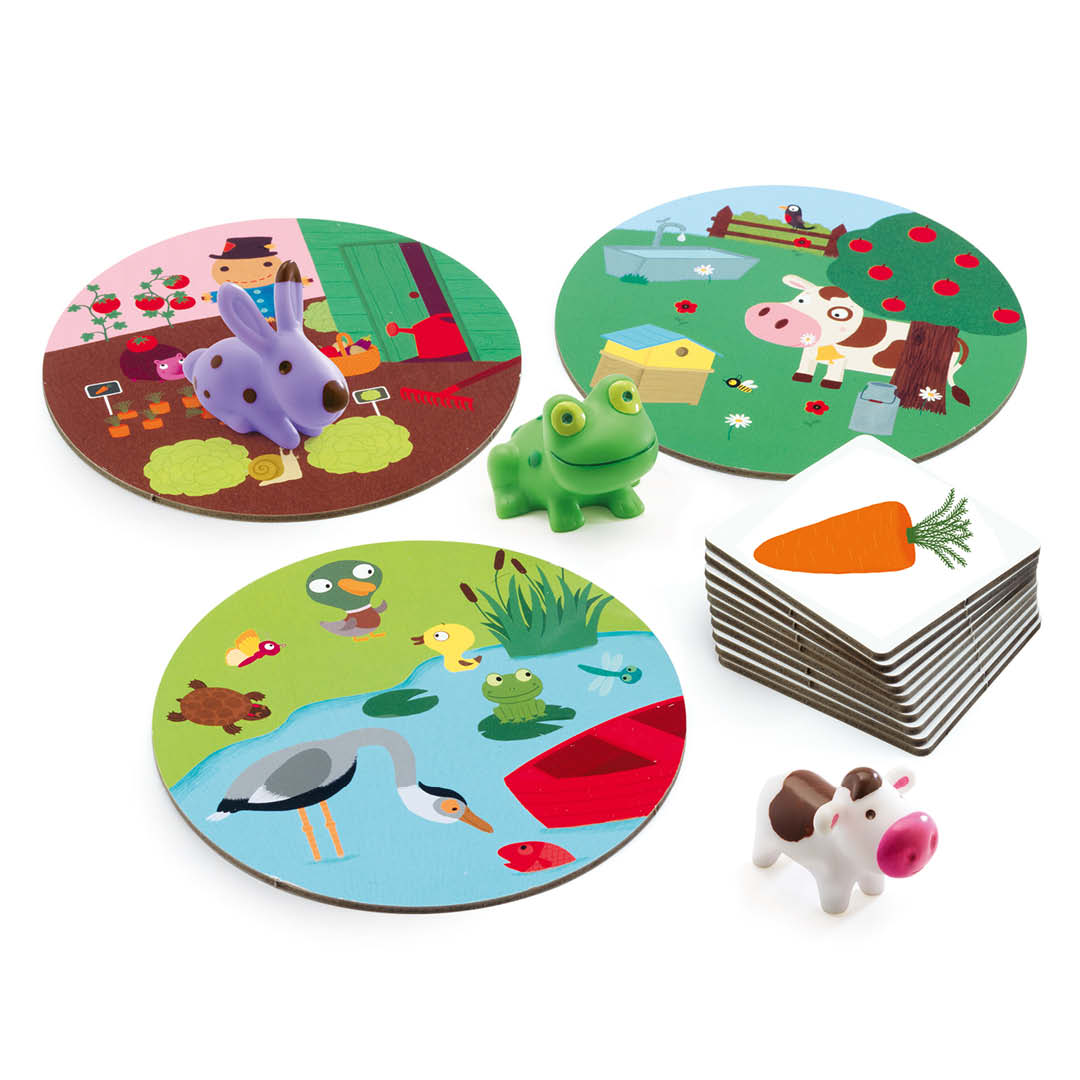 De speelstukken van het Little Association associatiespel, waaronder ronde speelborden, kaarten en plastic dierenfiguren van een konijn, kikker en koe.