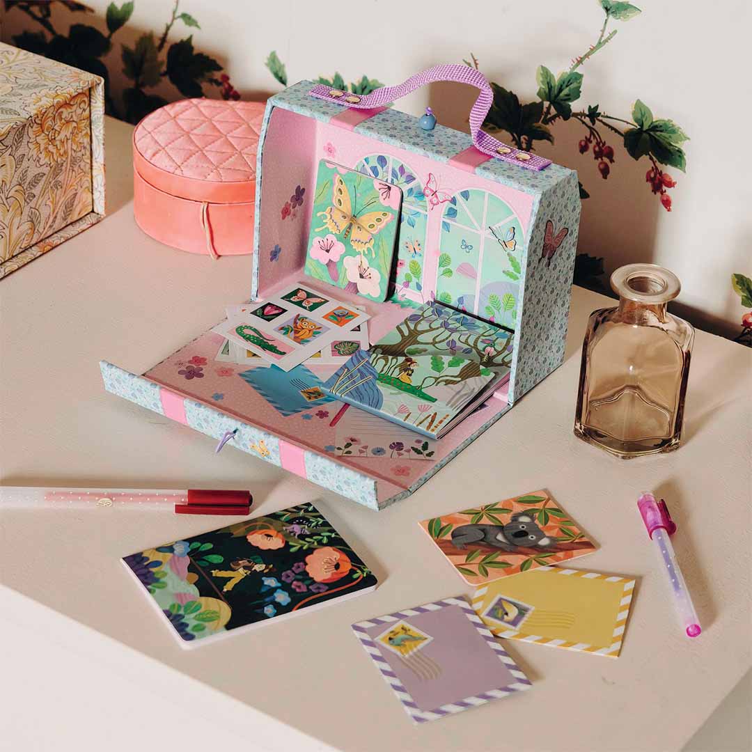 Djeco hobbyset met een open koffer vol briefpapier en kaarten met dieren, liggend op een dressoir met een pen en extra kaarten.