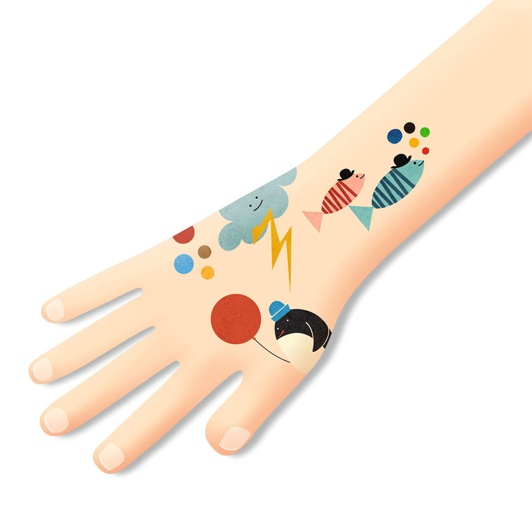 Een arm met daarop tijdelijke tatoeages van een pinguïn, vissen, een wolk en een bliksemschicht.