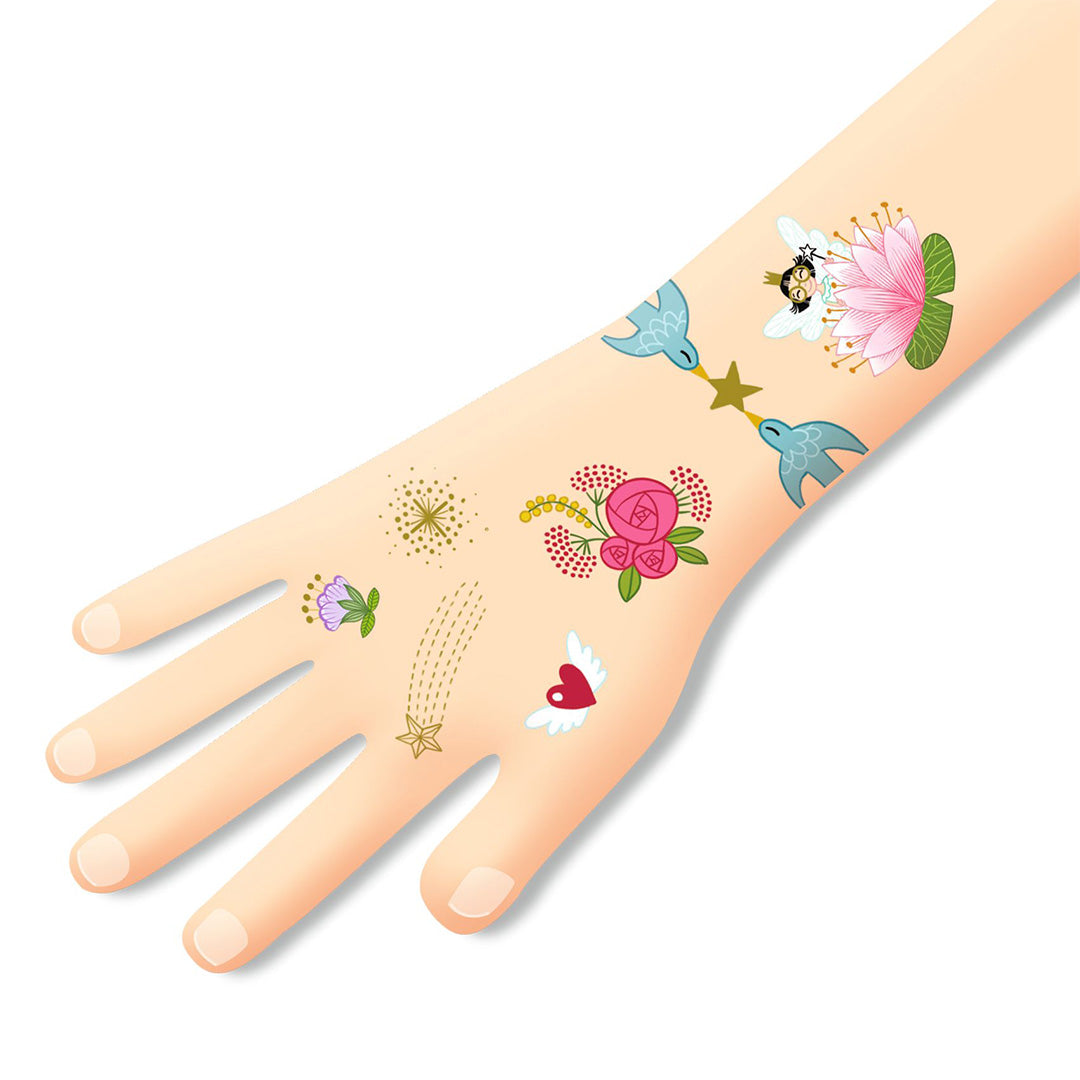 Een hand en onderarm met diverse tijdelijke tatoeages van sprookjesvrienden, bloemen en sterren.