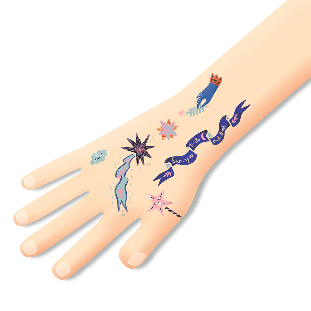 Een kinderhand met daarop verschillende tijdelijke tatoeages met droomwereld- en sterrenmotieven.