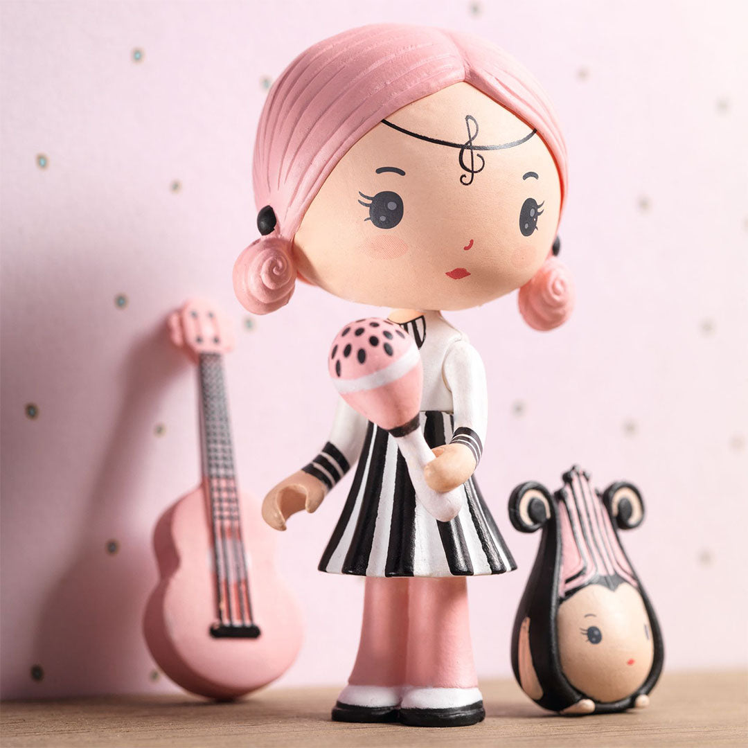 Djeco Tinyly speelfiguur Sidonie met roze haar en maraca, met gitaar en vriendje Zick op een houten ondergrond.