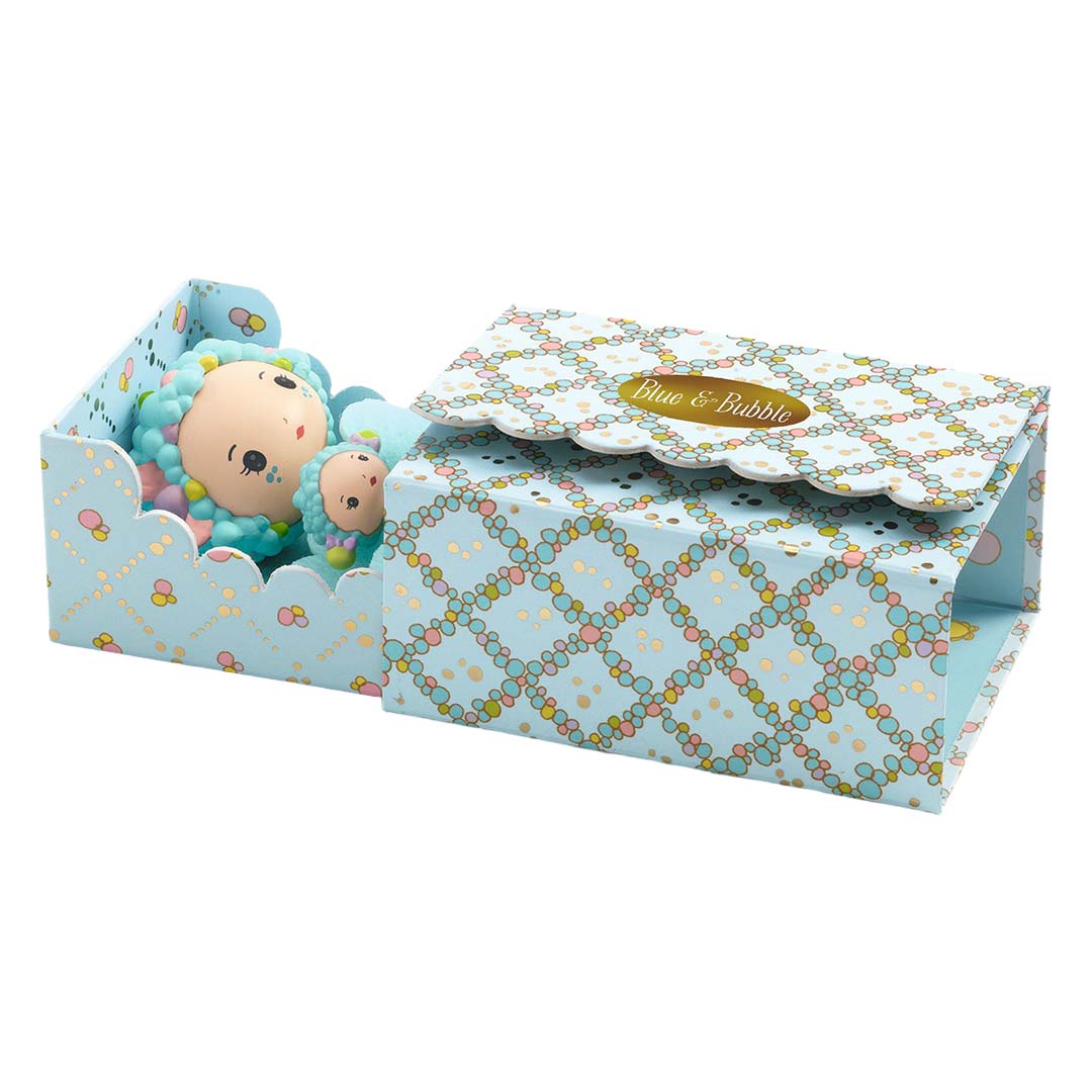 De Djeco Tinyly speelset Tinyroom Blue verpakking, deels opengeklapt, met de poppen in een bedje en een blauw patroon op de doos.