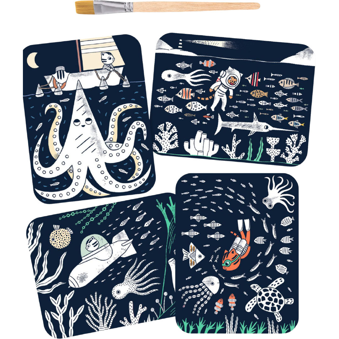 Vier oningekleurde kaarten van de magic reveal paint set met verschillende onderwater scènes en een kwast.