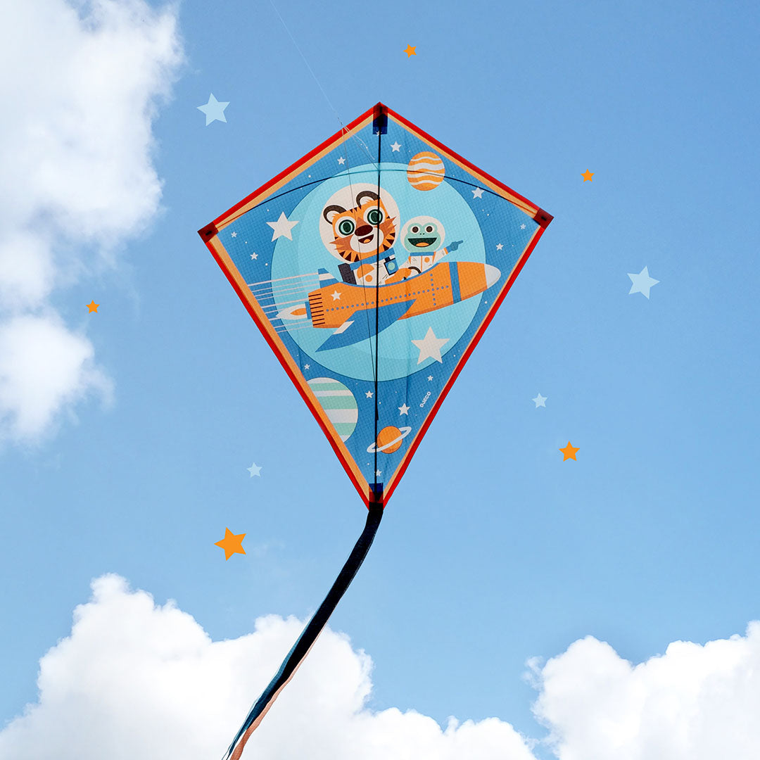 De Djeco vlieger met raketthema vliegt in een blauwe lucht met wolken.
