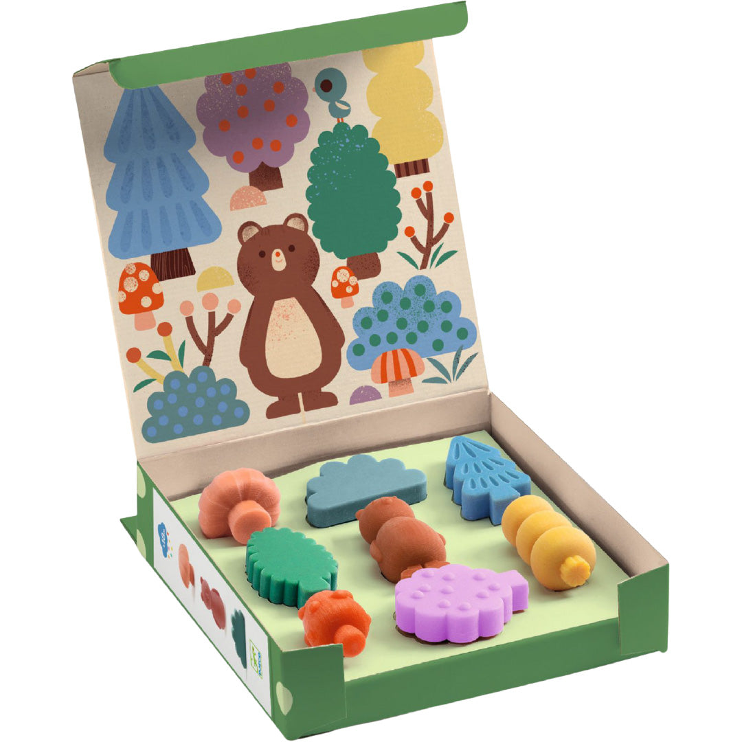 Open Djeco doos met waskrijtjes in bosvormen en een illustratie van een bos op de binnenkant van de deksel.