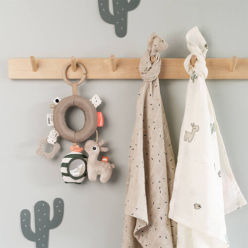 done by deer activiteitenring Lalee hangend aan een houten kapstokhaakje aan een grijze muur.