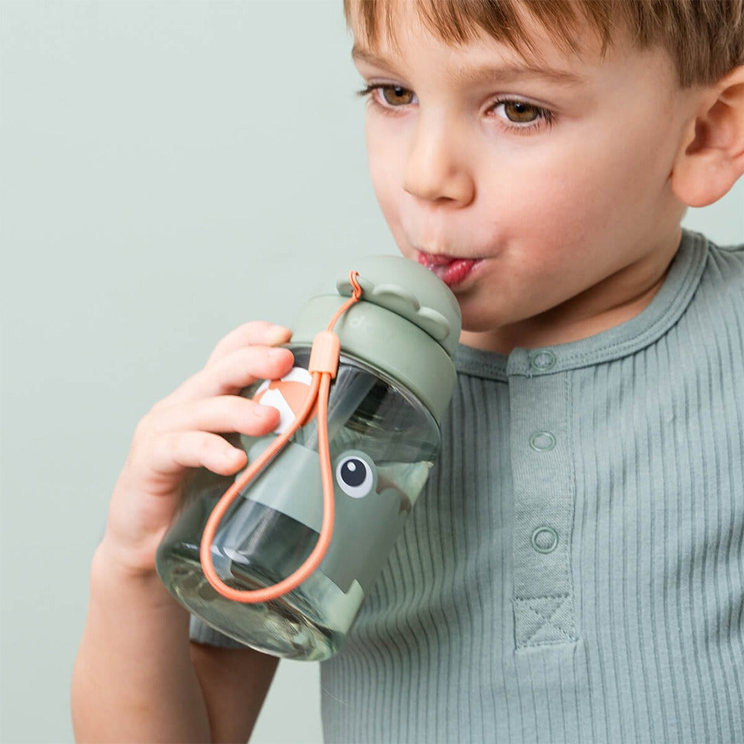 Een kind drinkt uit de done by deer drinkfles met rietje met krokodil design.