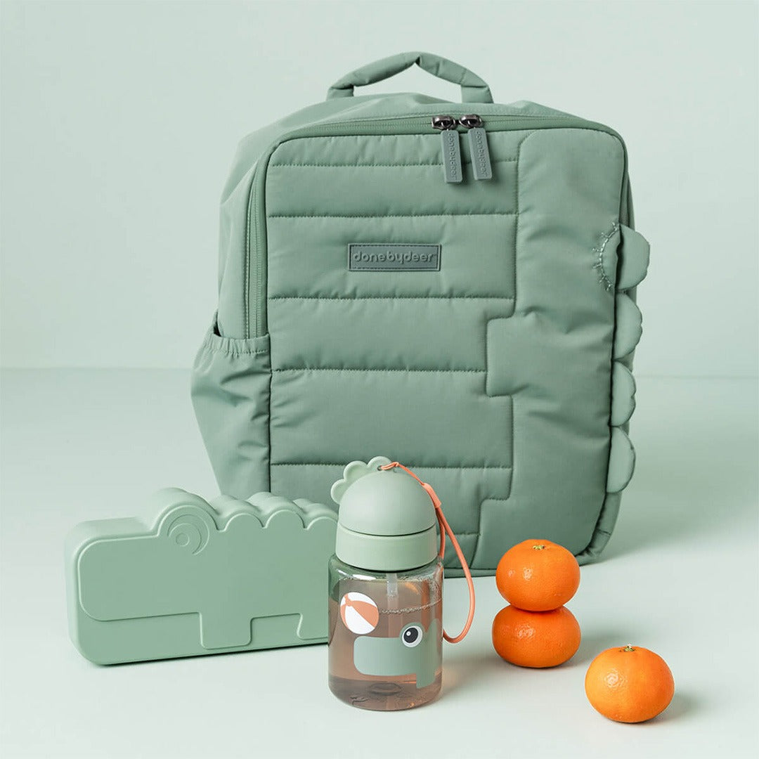 Done by deer drinkfles met rietje, rugzak en lunchbox met krokodil design, naast drie mandarijnen.