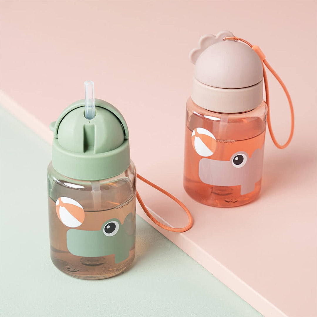 Twee done by deer drinkflessen met rietje voor kinderen, één beige en één groen, met nijlpaard en strandbal.