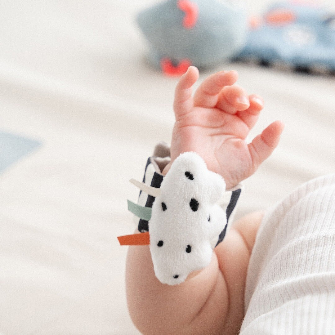De done by deer polsrammelaar met witte wolk en gekleurde labels om de arm van een baby.