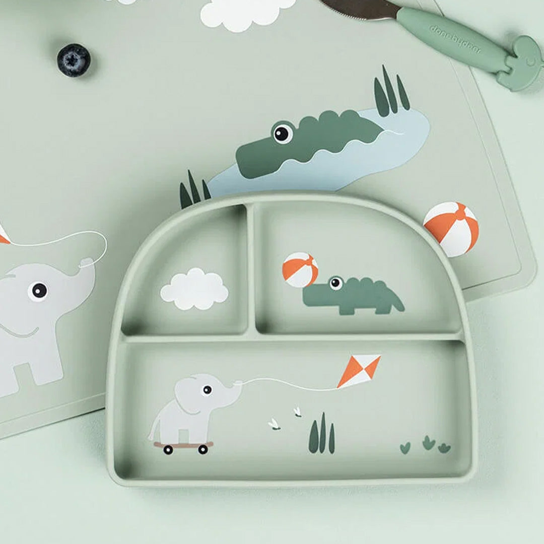 done by deer groen siliconen 3-vakjesbord voor baby's met dierenprint, liggend op een bijpassende placemat.
