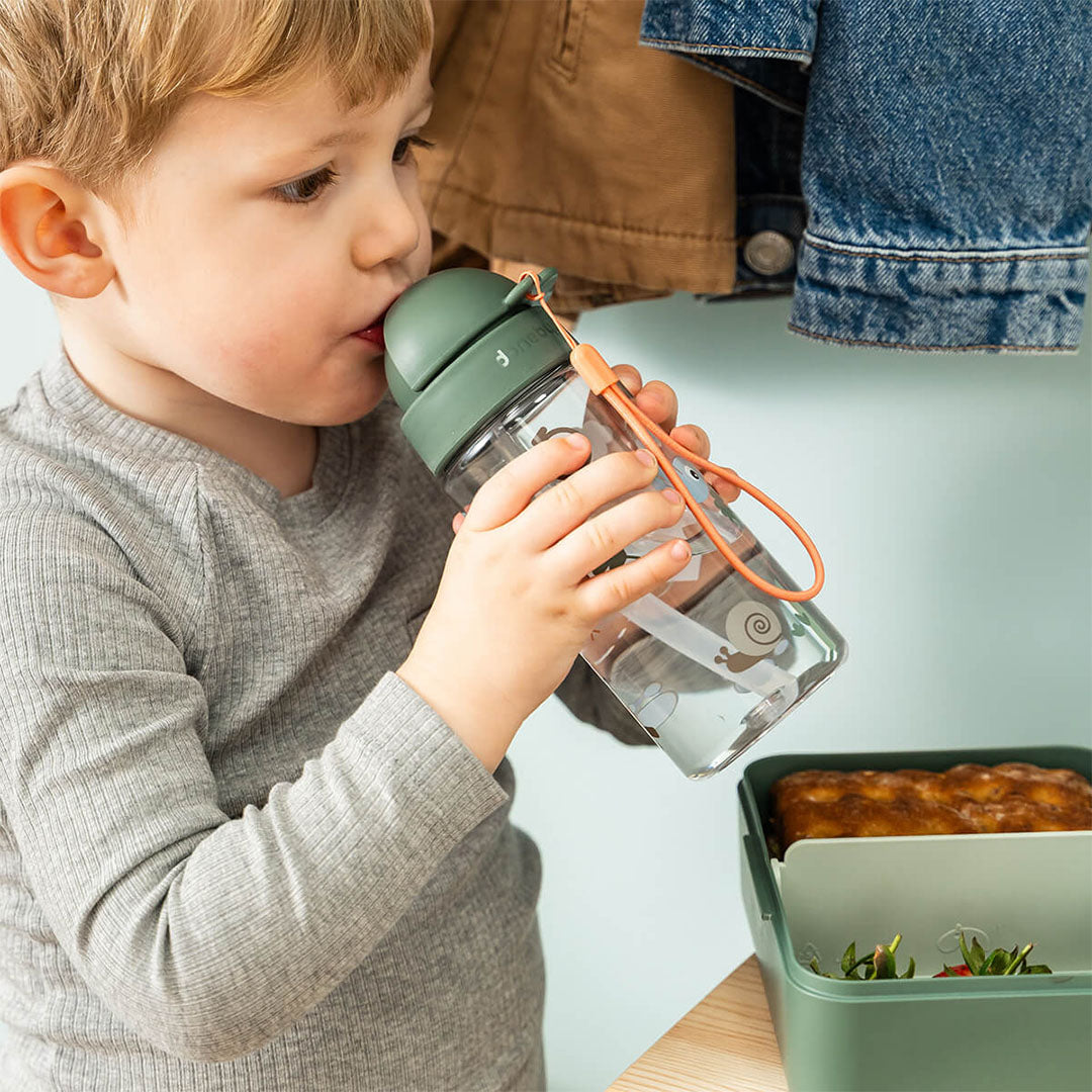 Een kind drinkt uit de Done by Deer drinkfles met rietje Tiny Trails met groene dop.