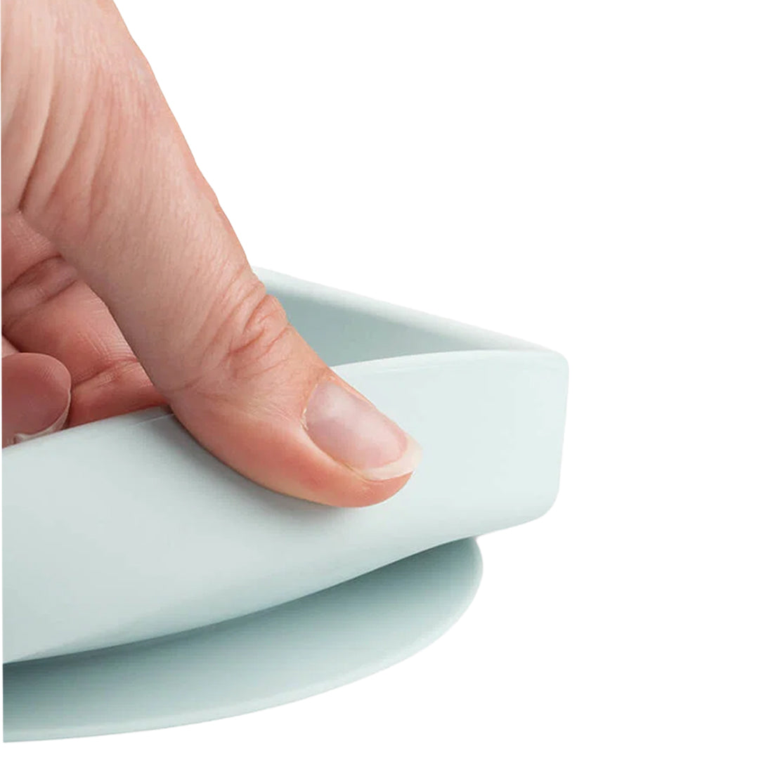 Detail van een hand die de flexibele rand van het Done by Deer siliconen kinderbord vasthoudt.