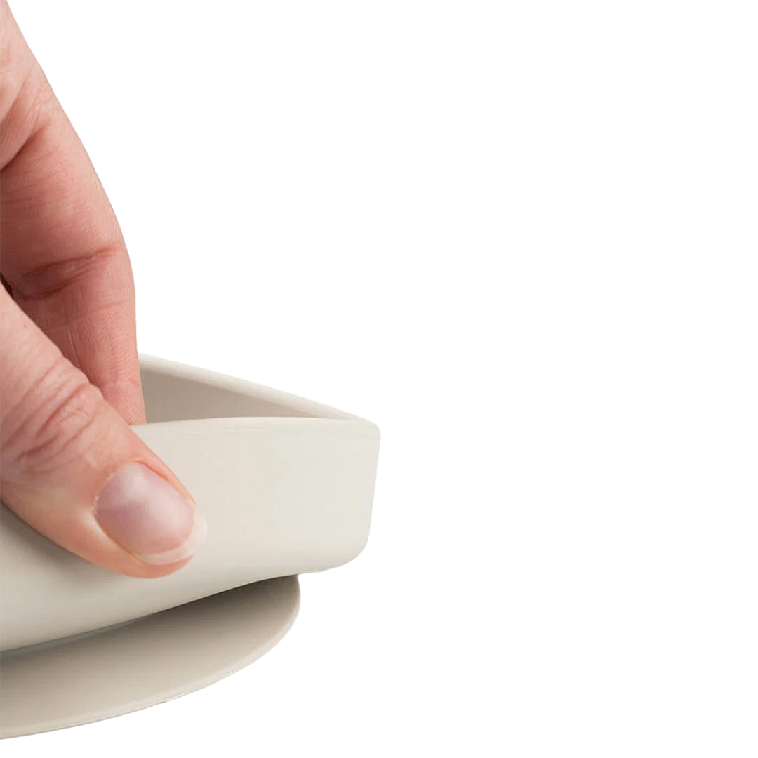 Detail van een hand die de flexibele rand van het siliconen kinderbord vasthoudt.