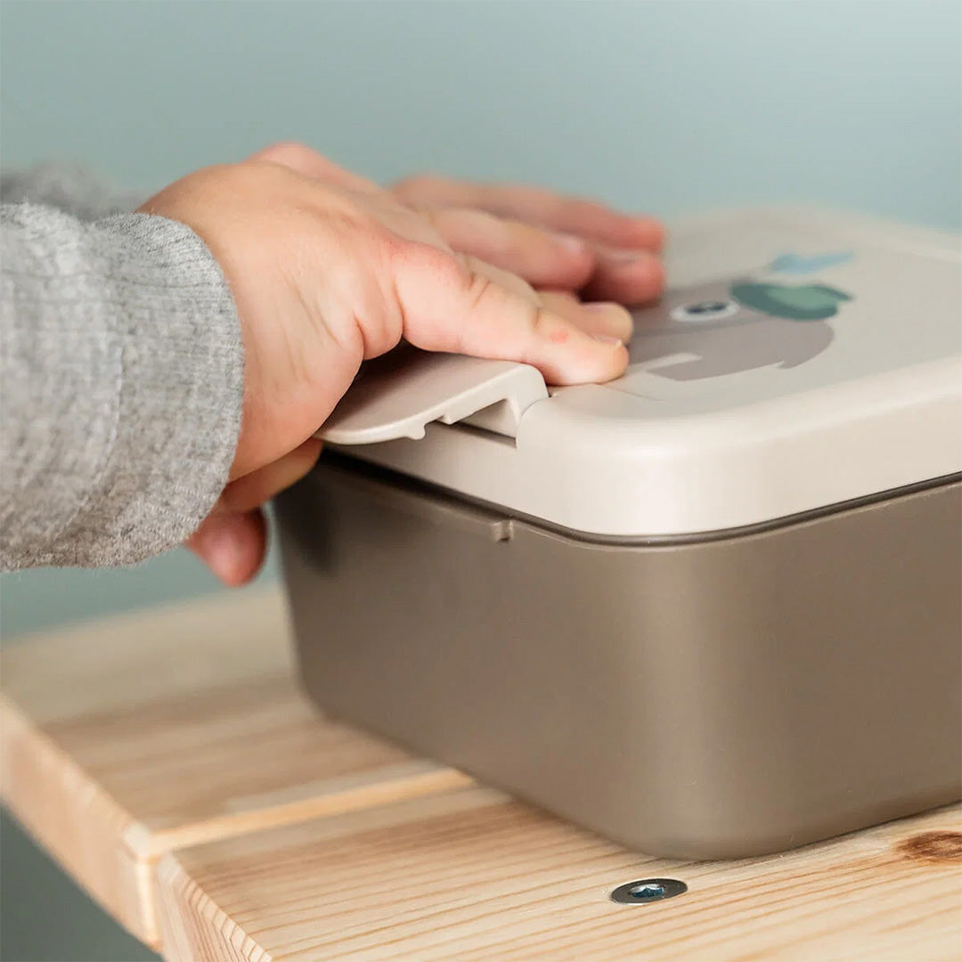 Een hand sluit de Done by Deer lunchbox met de sluiting.