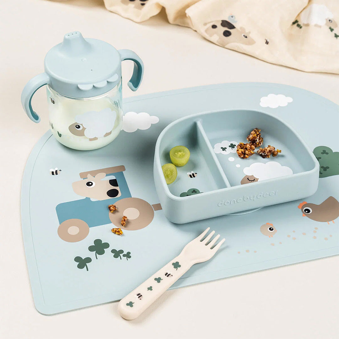 Done by Deer placemat Tiny Farm met een bijpassend blauw babybord, drinkbeker en vorkje.