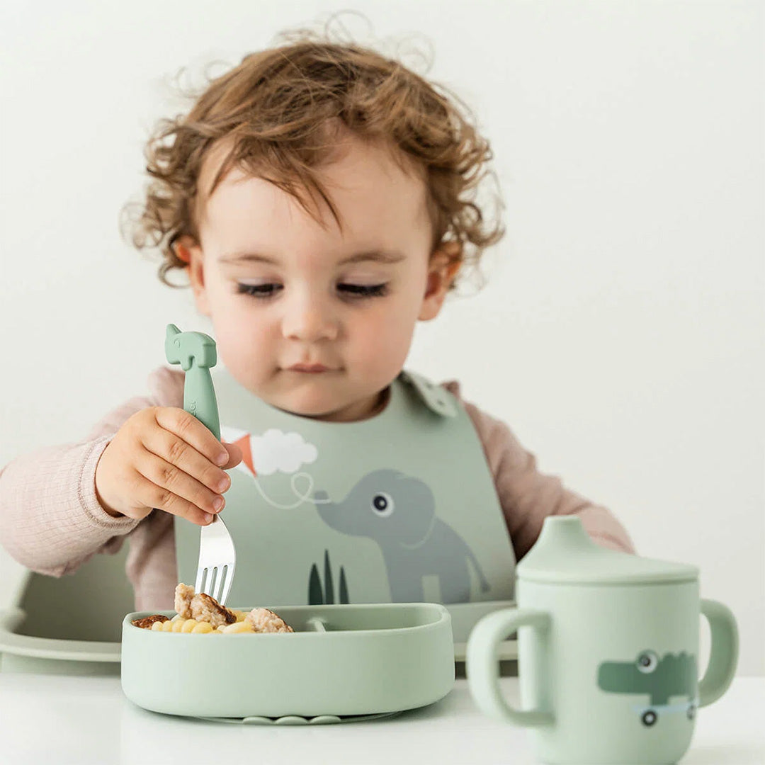 Baby eet met een Done by Deer groen siliconen kommetje en vork, met bijpassende slab en beker.