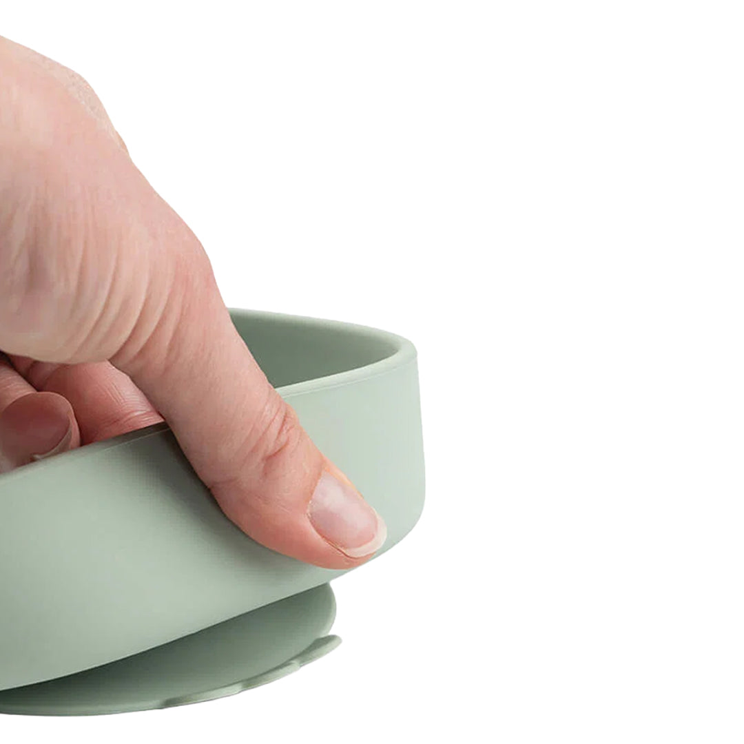 Hand houdt de rand vast van een Done by Deer groen siliconen babykommetje met zuignap.