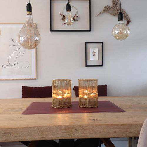 Rode eeveve bureaumat op een houten eettafel met twee gouden theelichthouders.