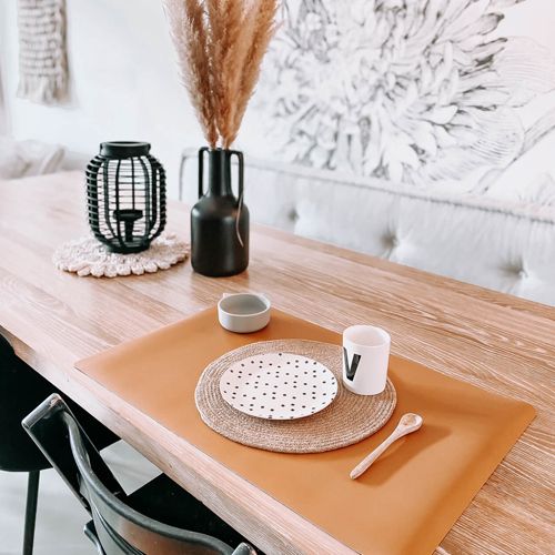 eeveve mosterdkleurige bureaumat op een houten eettafel, gedekt met servies.