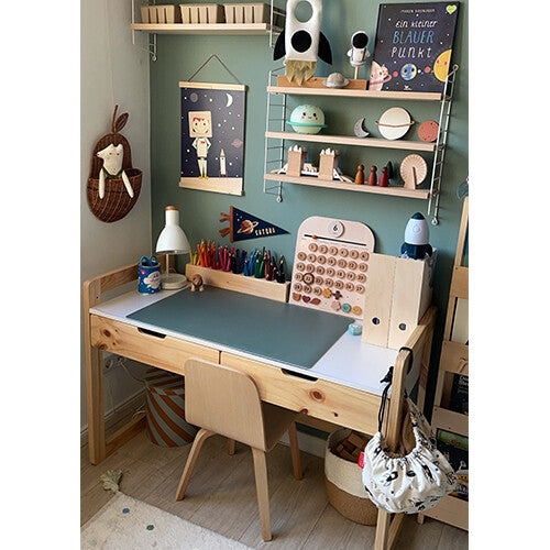 Een groene eeveve bureaumat op een houten kinderbureau met schoolspullen.