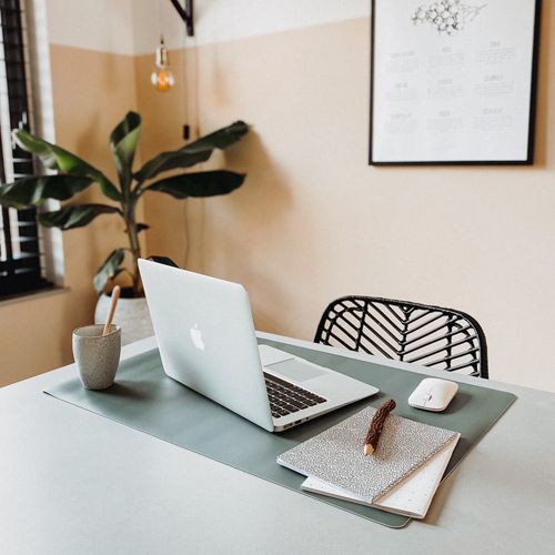 Een groene eeveve bureaumat met een laptop en kantoorbenodigdheden op een bureau.