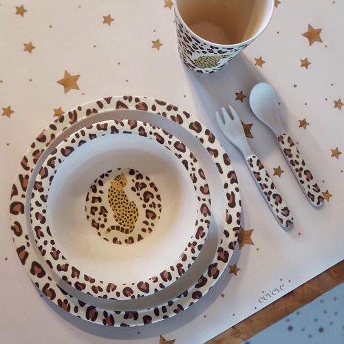 eeveve bureaumat met sterrenpatroon waarop kinderservies met luipaardprint staat.