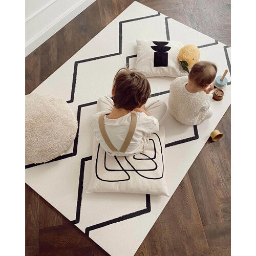 Twee kinderen spelen op de eeveve foam speelmat met zwart geometrisch patroon.