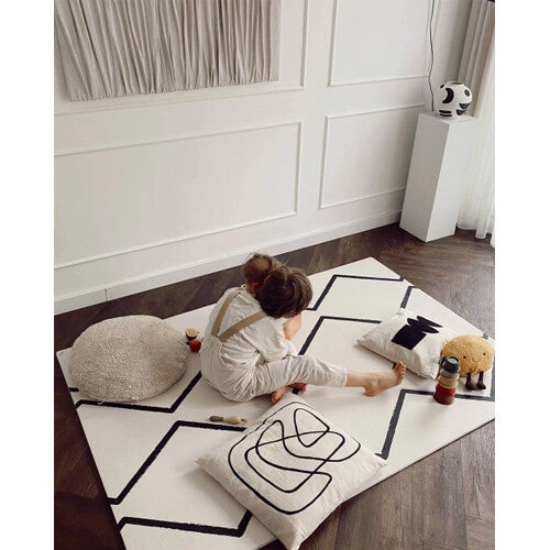 Twee kinderen spelen zittend op de eeveve foam speelmat met zwart geometrisch patroon.