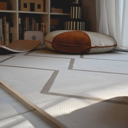 Detail van de eeveve foam speelmat met beige geometrisch patroon op de vloer in een kinderkamer.